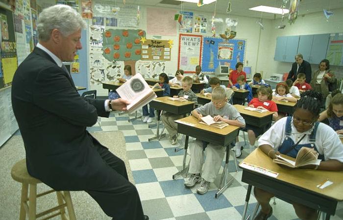 Clinton reading a book to elementary school children.